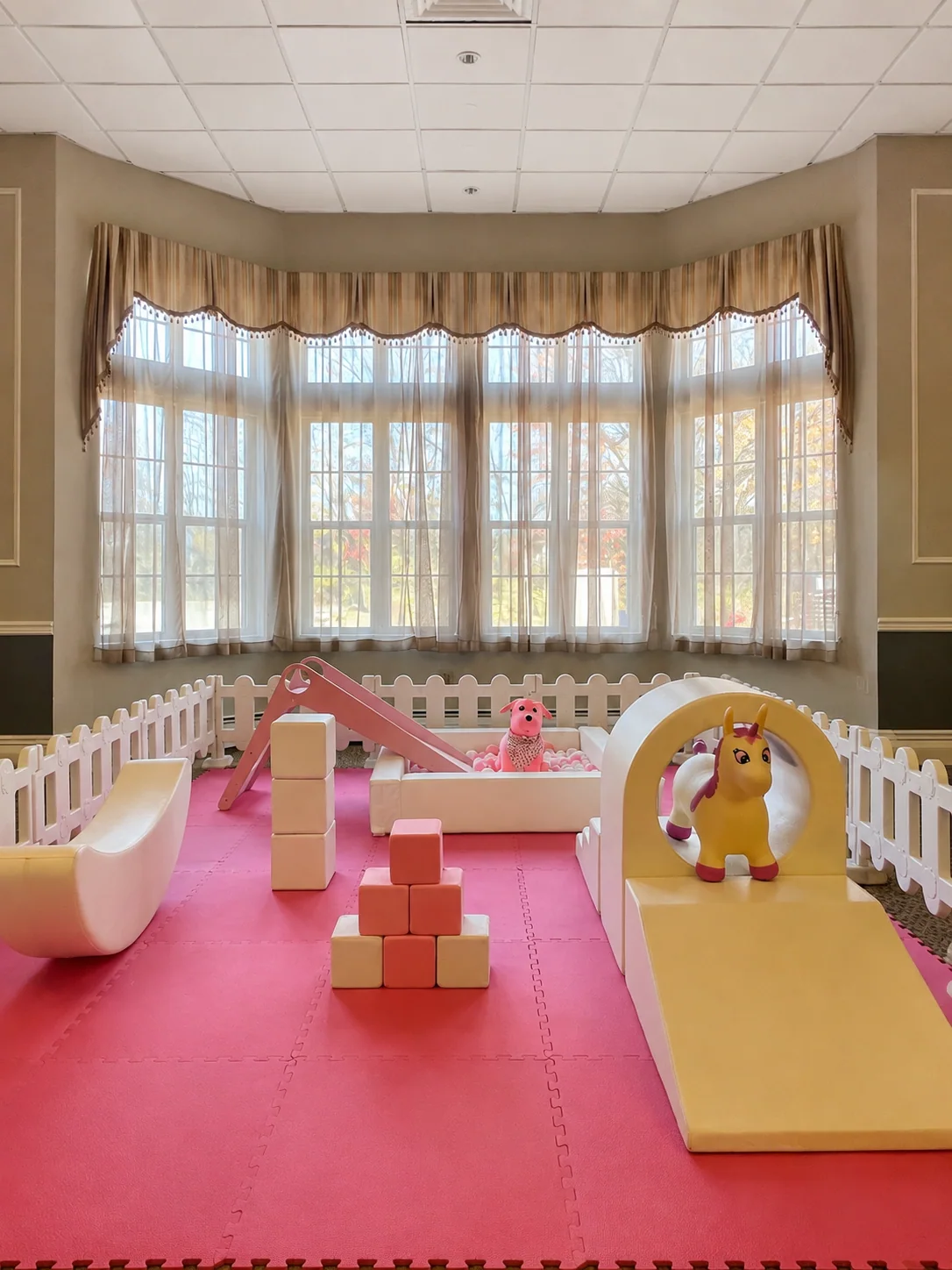 Pink and yellow indoor soft play setup in a bright event room
