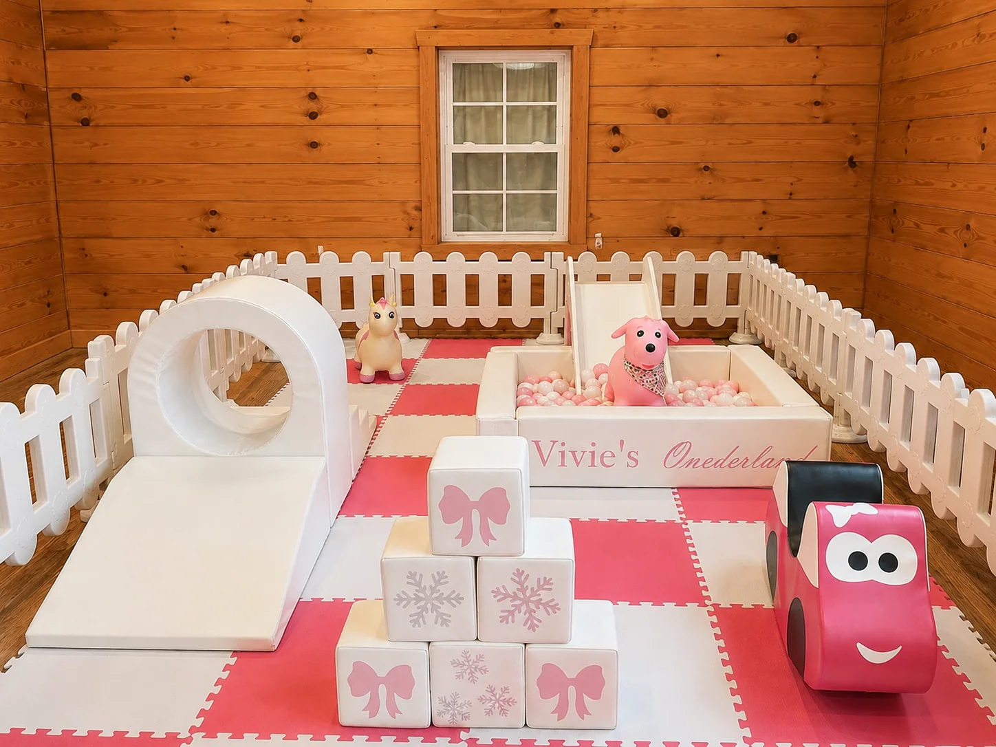 Pink and white premium soft play setup in a warm indoor event room